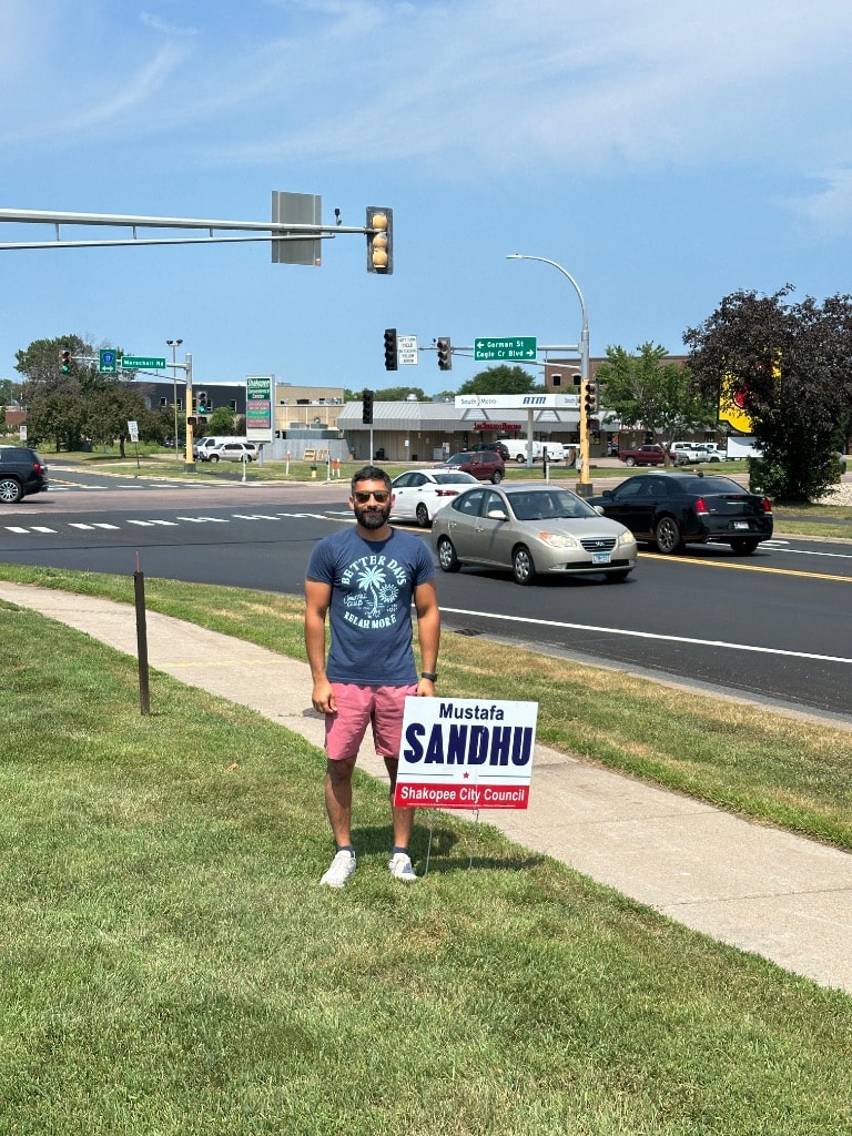 Man holding a political campaign sign roadside