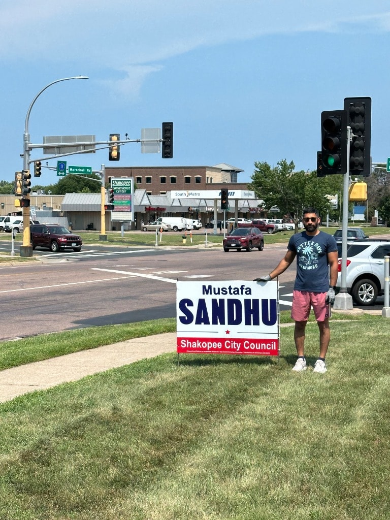 Man holding a political campaign sign outdoors