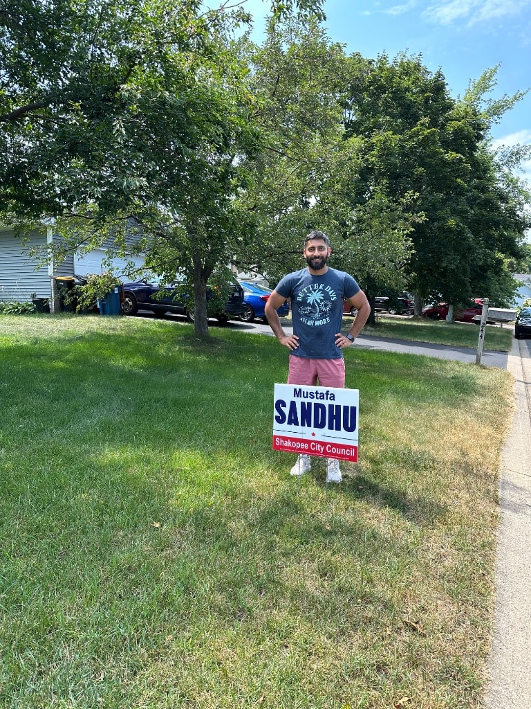Man posing with a political campaign yard sign