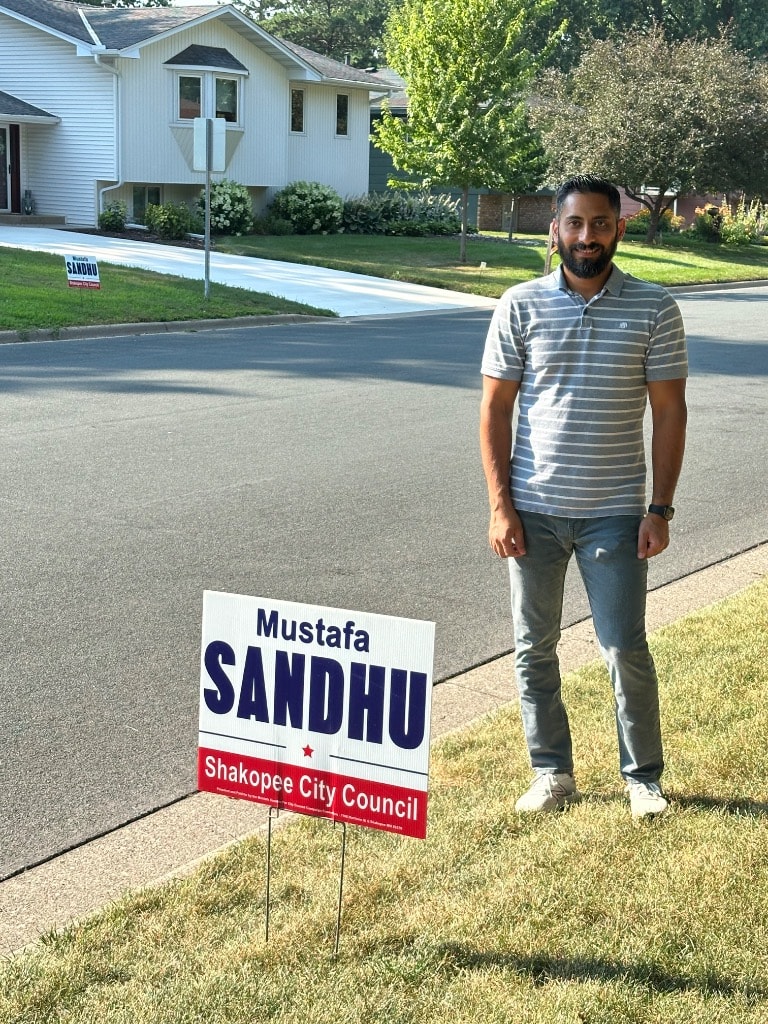 Man posing with a political campaign yard sign