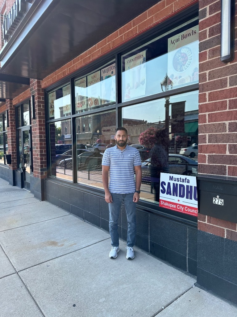 Mustafa Sandhu standing outside a storefront brick building