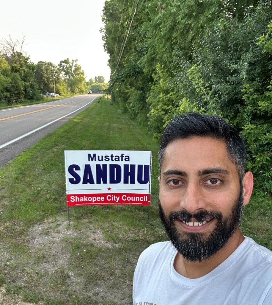 Man posing with a political campaign sign roadside