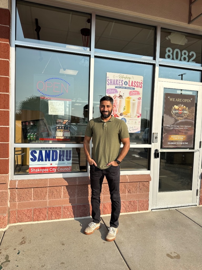 Man standing outside an Indian restaurant storefront