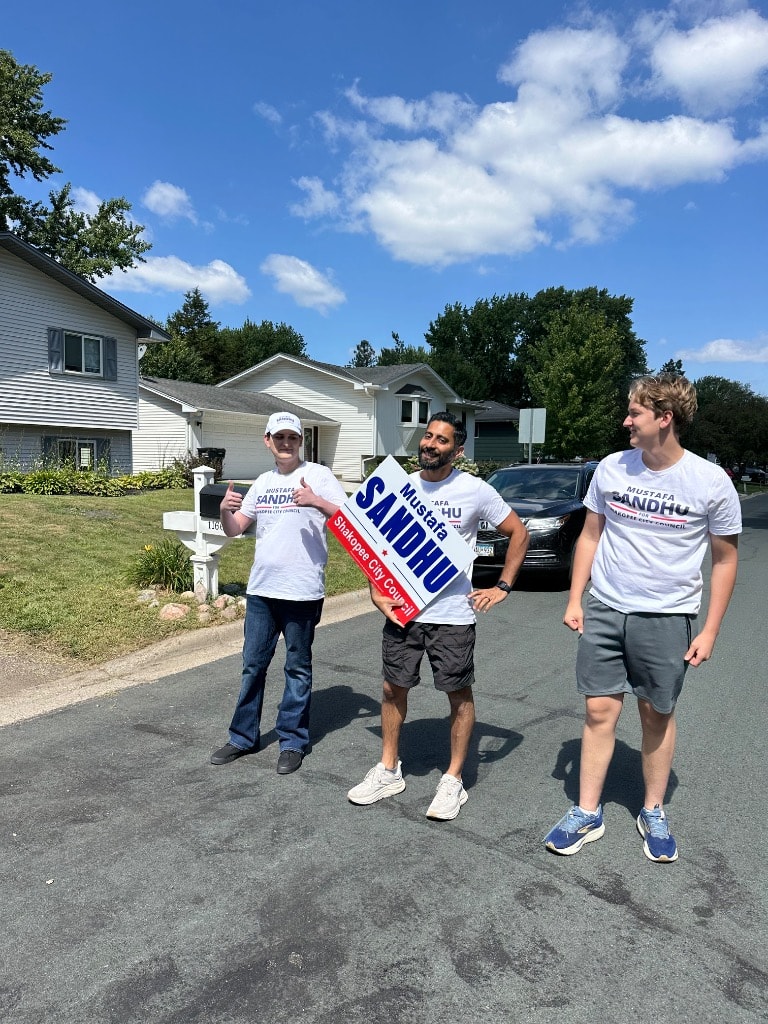 Campaign volunteers holding political signs on a residential street