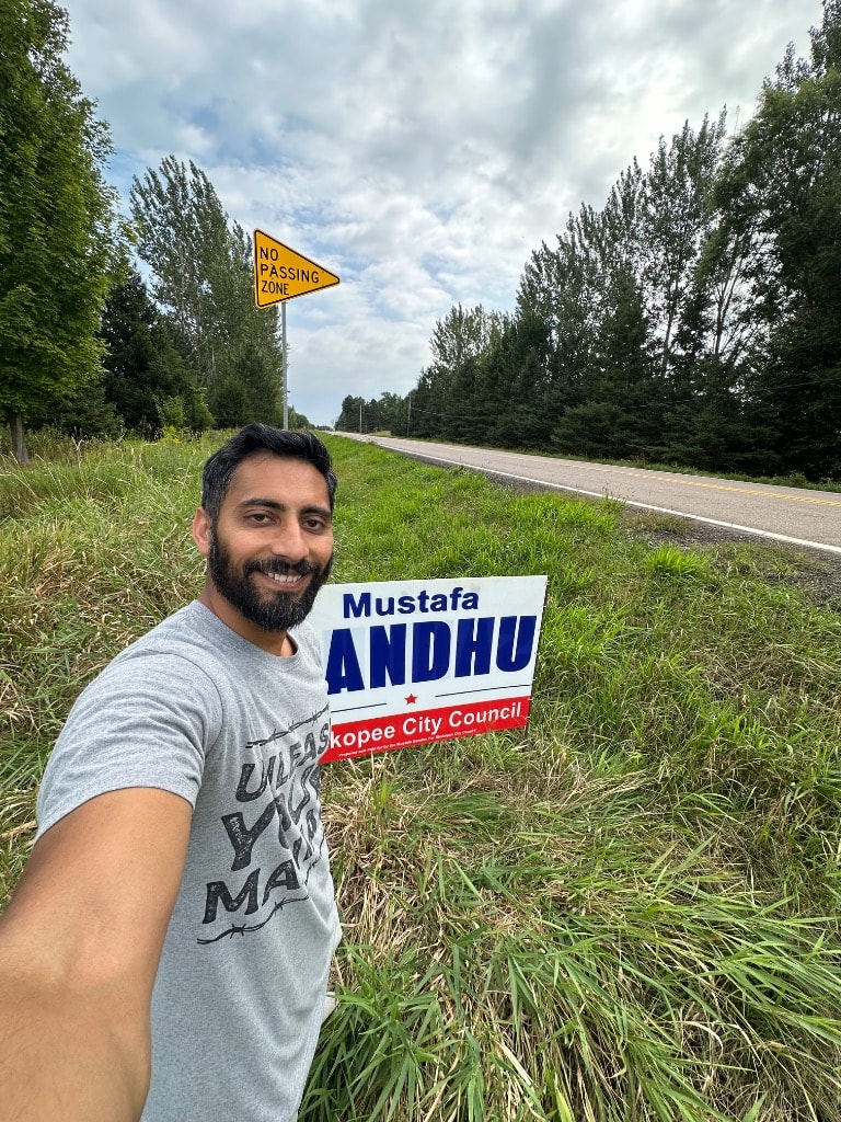Man holding a political campaign sign roadside