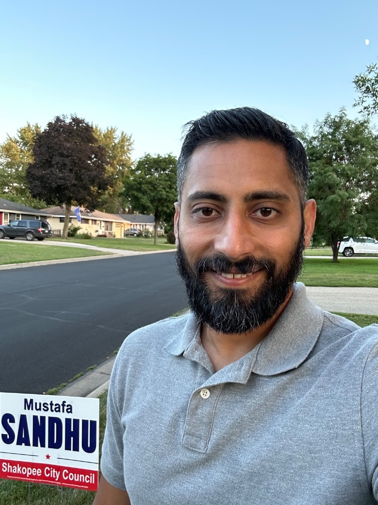 Mustafa Sandhu with a campaign sign on a residential street