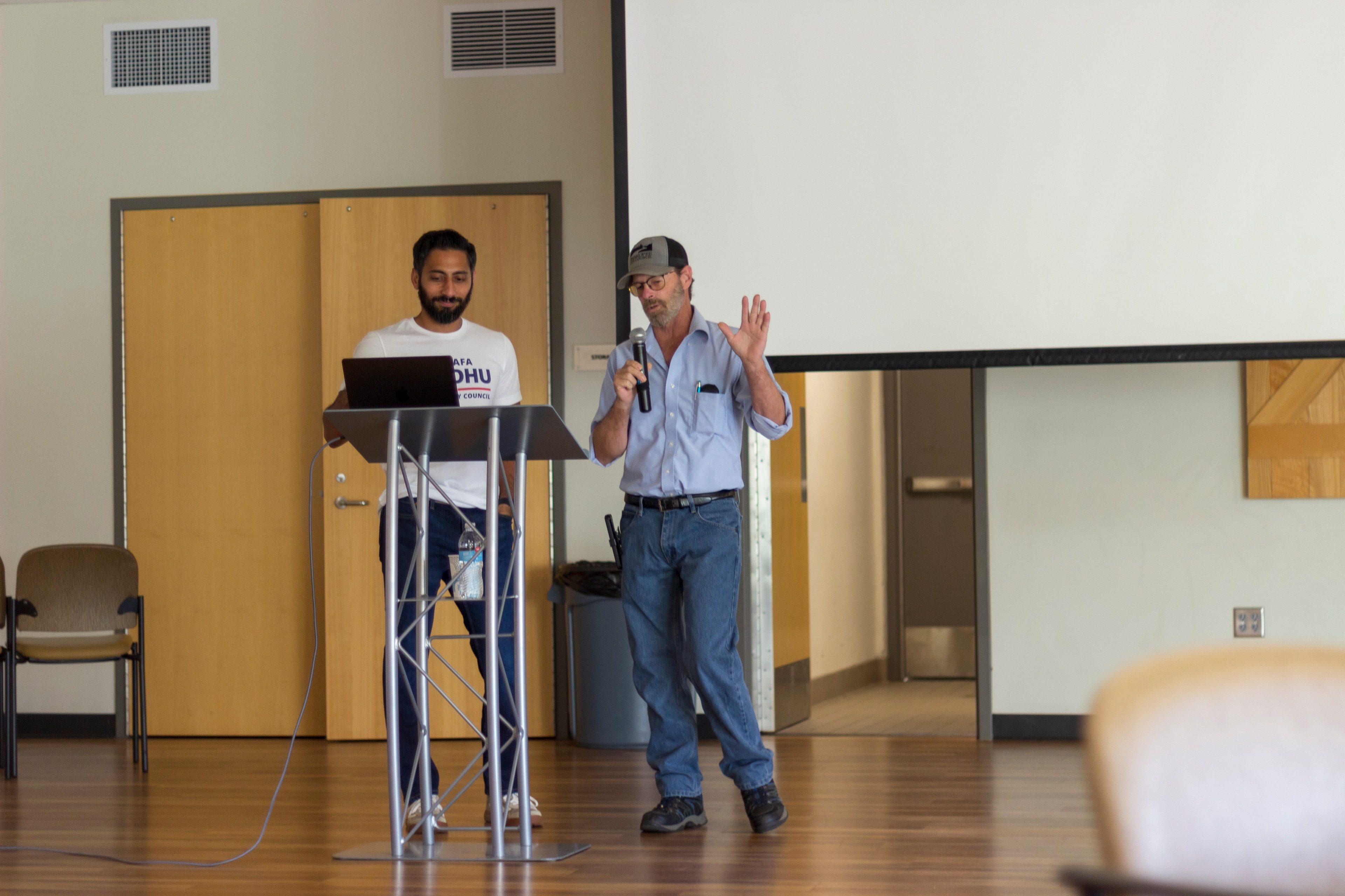 Mustafa Sandhu at podium with a community speaker at the meet and greet