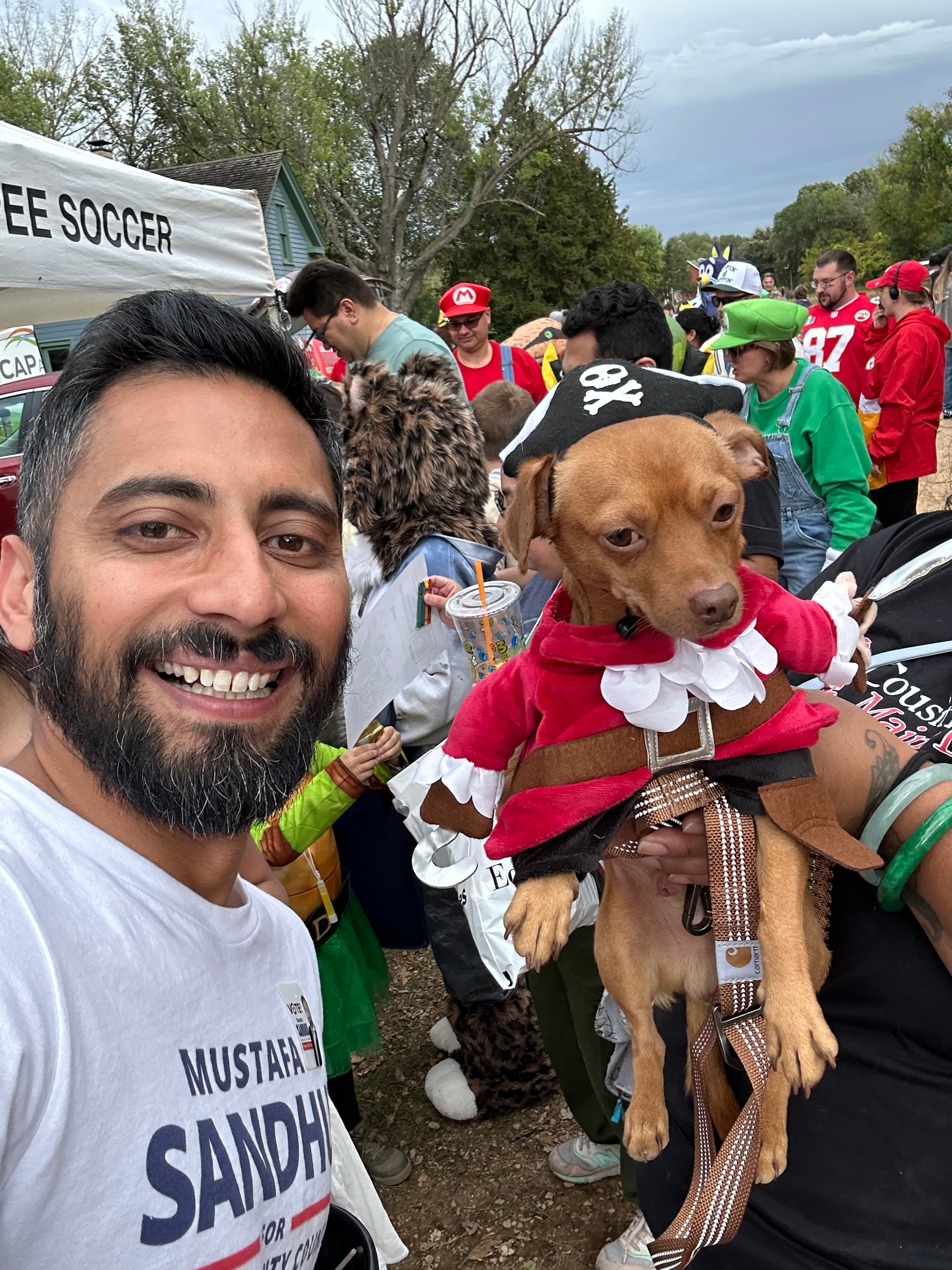 Mustafa Sandhu selfie with costumed dogs at the trunk-or-treat gathering