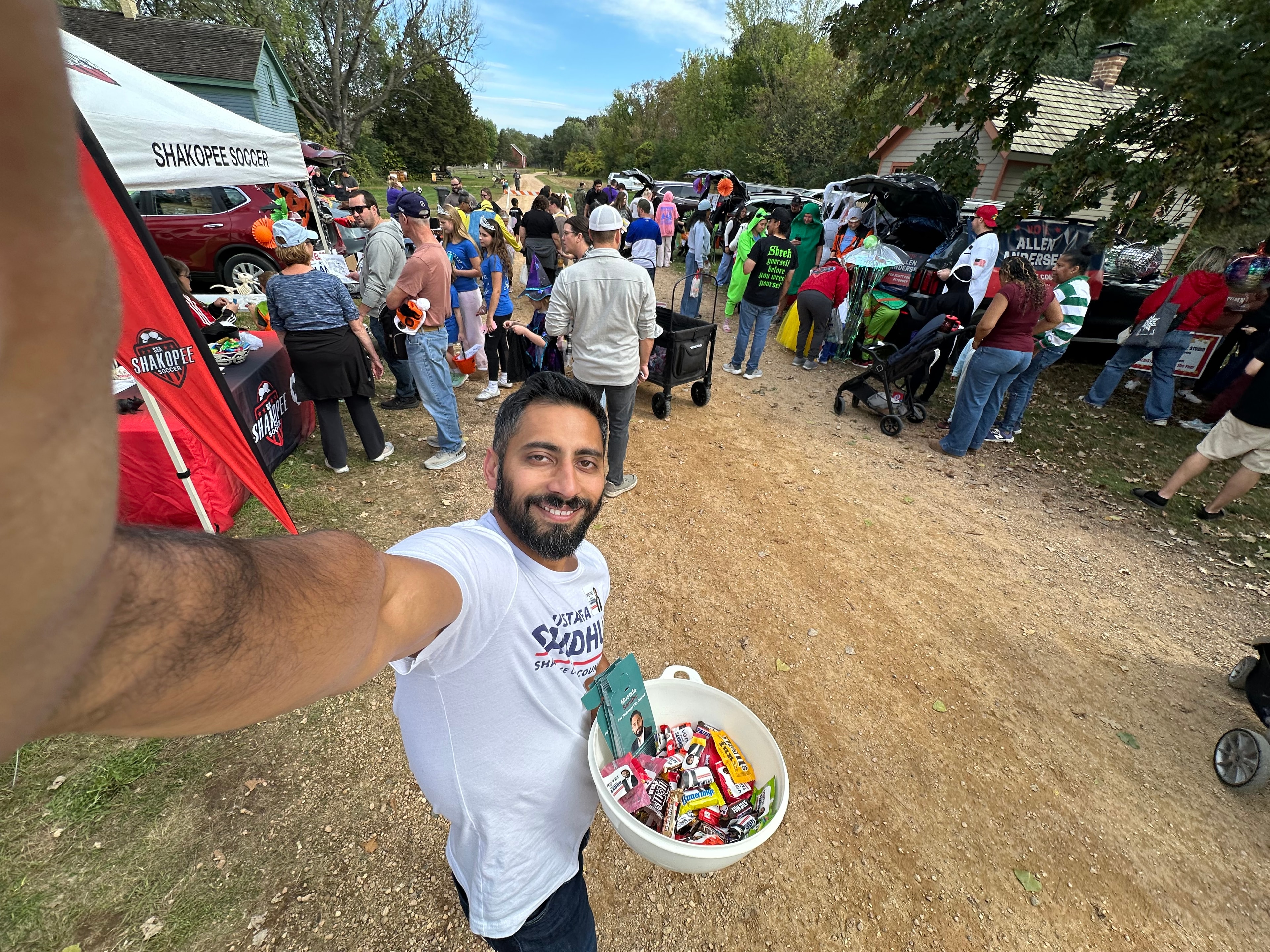 Mustafa Sandhu holding candy bowl at the busy trunk-or-treat event