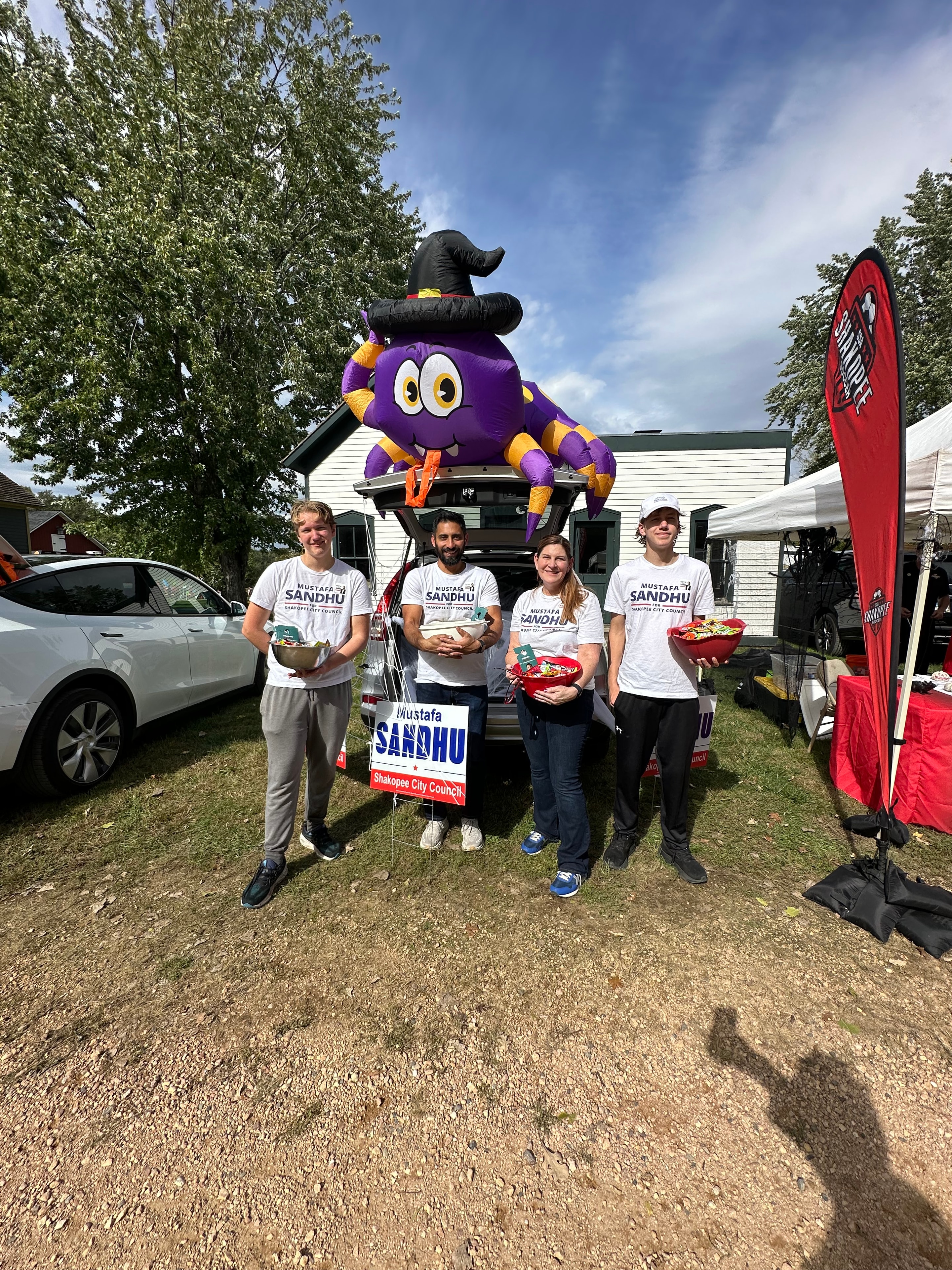 Mustafa Sandhu and campaign volunteers posing with inflatable spider at the event