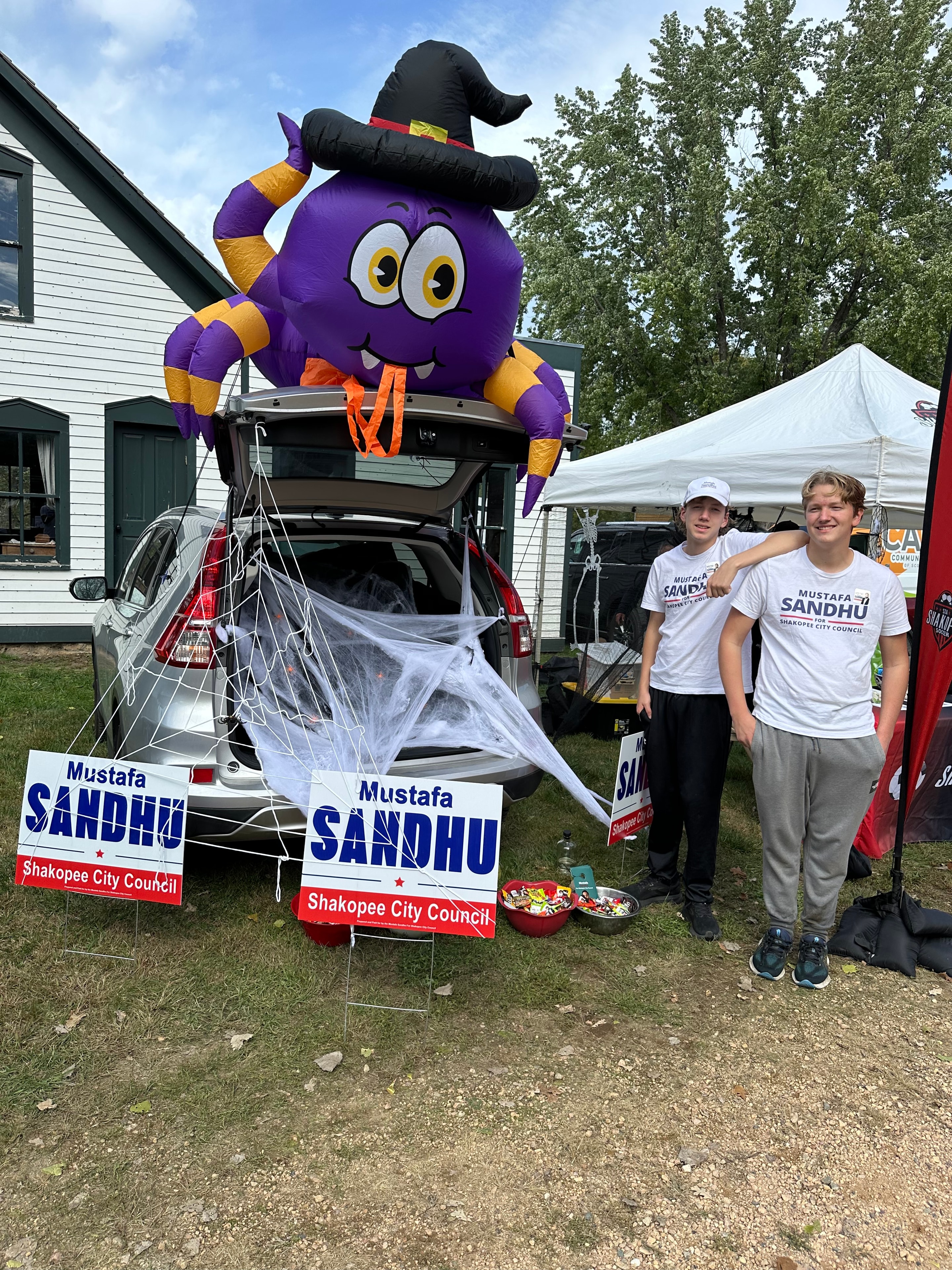Young campaign volunteers posing with inflatable spider and Sandhu campaign signs