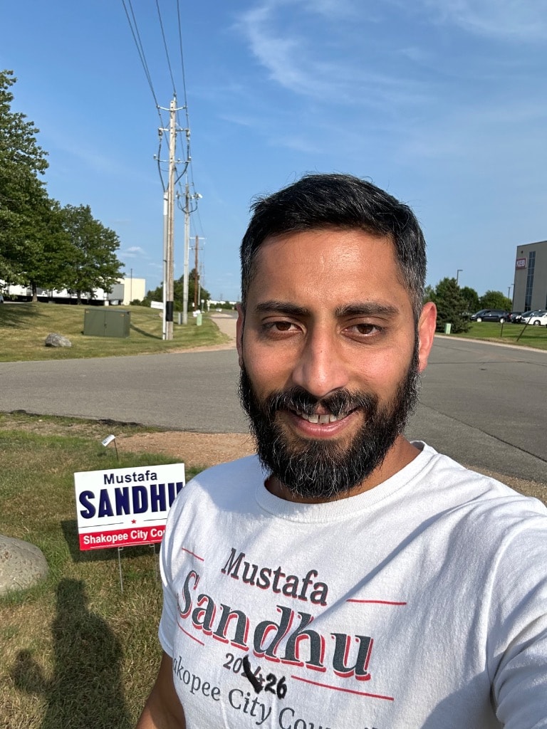 Mustafa Sandhu with a campaign sign outdoor portrait